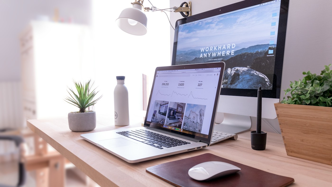 MacBook Pro en la mesa junto al iMac blanco y el Magic Mouse