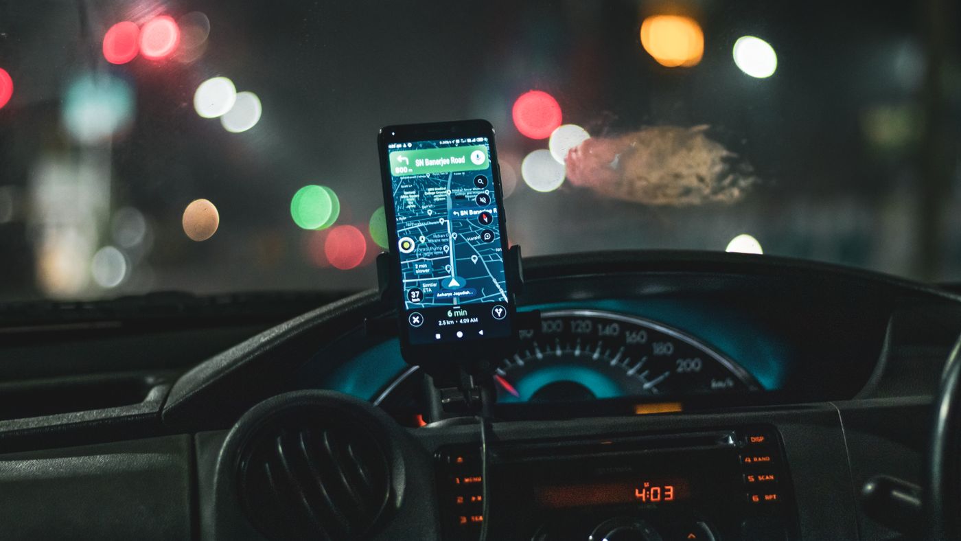 Primer plano de un smartphone con navegación por mapa en un coche por la noche con efecto