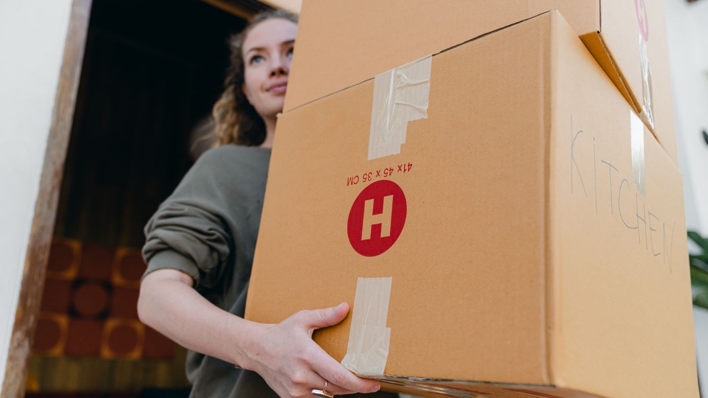 Mujer joven y segura llevando cajas de cartón durante un día de mudanza